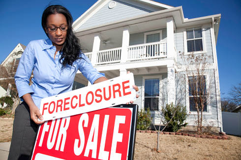 Woman putting foreclosure sign on house | Foreclosure, mortgage and charge off